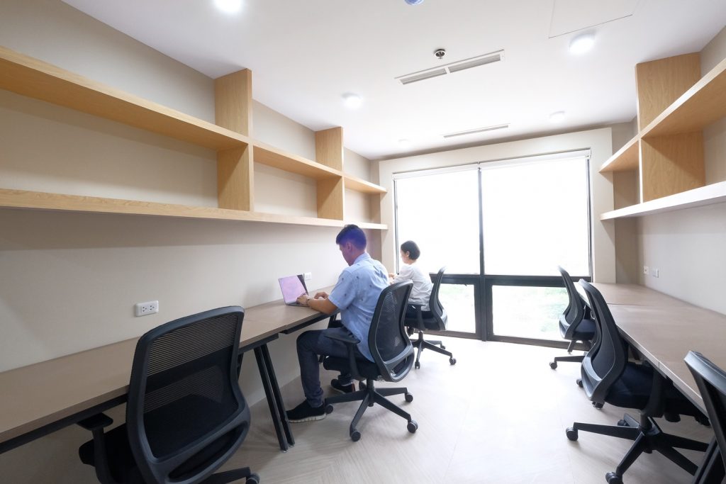 Minimalist shared workspace with desks, shelving, and a private office at M Spaces.