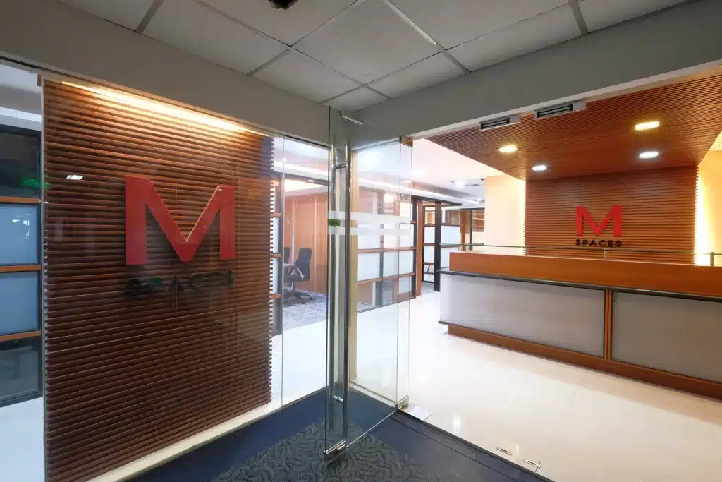 Modern office entrance and reception area featuring the M Spaces logo and wood paneling.