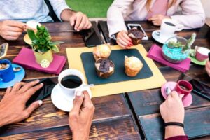 People enjoying coffee and muffins at an outdoor café table