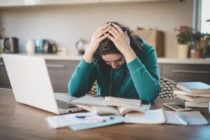 Woman looking stressed while working on a laptop at home