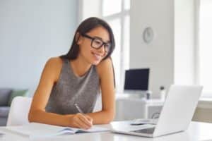 Young woman smiling while working on a laptop at a desk