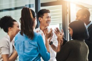 Group of colleagues celebrating and laughing in an office.