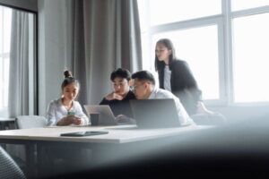 Team of young professionals collaborating with laptops in a conference room.