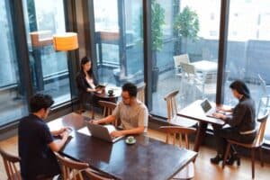 People working on laptops and reading books in a cozy cafe during rainy weather.