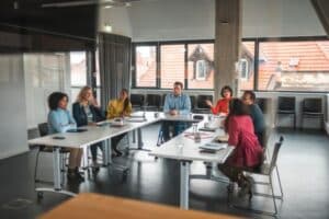 A diverse group of people in a casual office meeting on U table layout