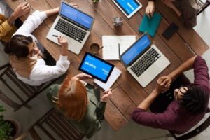 Overhead view of coworkers using laptops in a meeting.