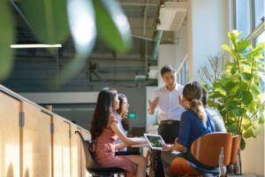 Business team having a discussion at a table near large windows and plants.