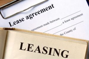 Lease agreement document on a clipboard next to a folder labeled leasing.