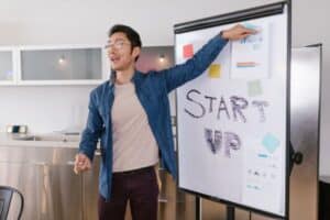 A man points to a whiteboard displaying the words "start up"