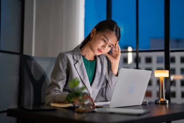 Woman working late on laptop in office.