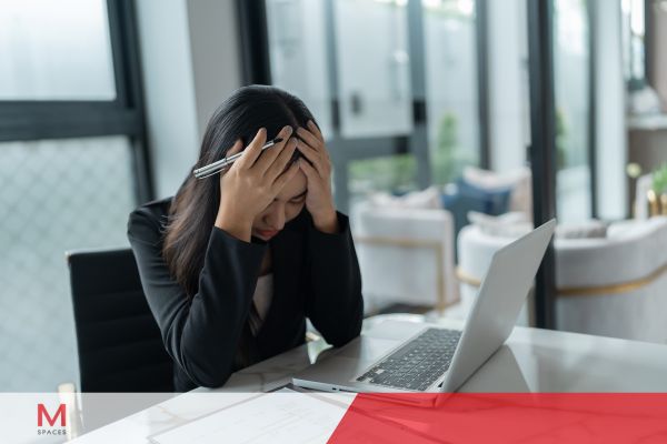 A woman in a business suit sits at her desk, head in hands, reflecting the stress of holiday blues.