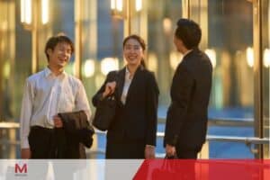 Three colleagues discussing work matters in front of a modern glass building, highlighting work-life balance in Makati.