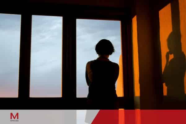 A woman in front of a window reflects on coworking spaces in Makati or BGC.