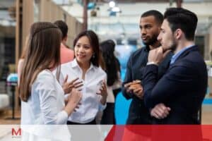 A group of people engaged in conversation inside a modern office building, collaborating in a coworking space.