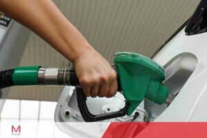 Close-up of person refueling white car at gas station with green fuel nozzle