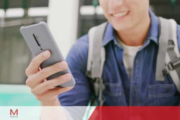 Young man using smartphone mobile app while commuting outdoors