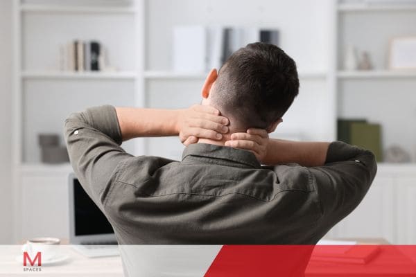 Office worker stretching neck and shoulders to relieve pain and stress while working from home.