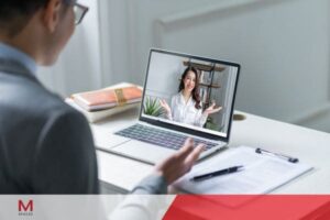 Professional attending a virtual online business meeting through a laptop video call from home office.