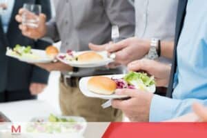 Business professionals holding plates with salad and bread rolls at a corporate buffet lunch event