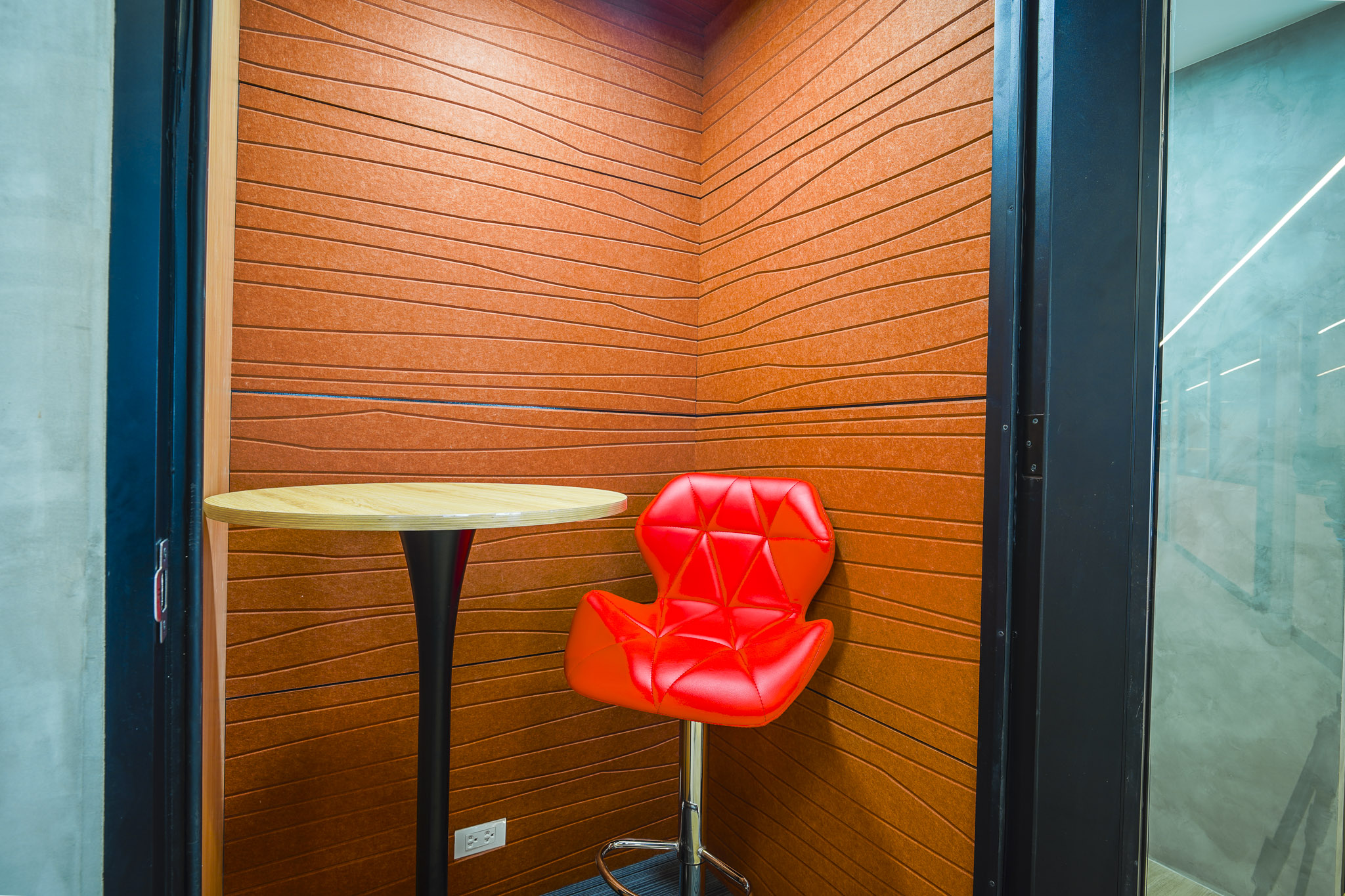 Private phone booth with table and red chair
