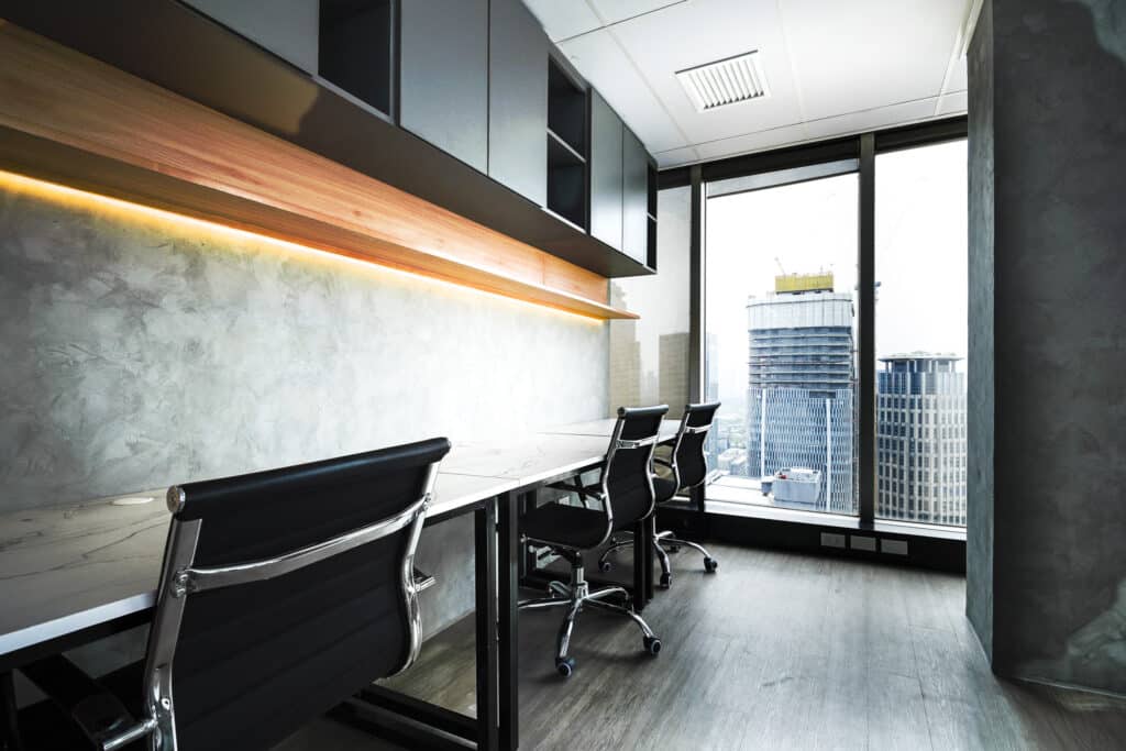 Modern office desks beside floor-to-ceiling windows