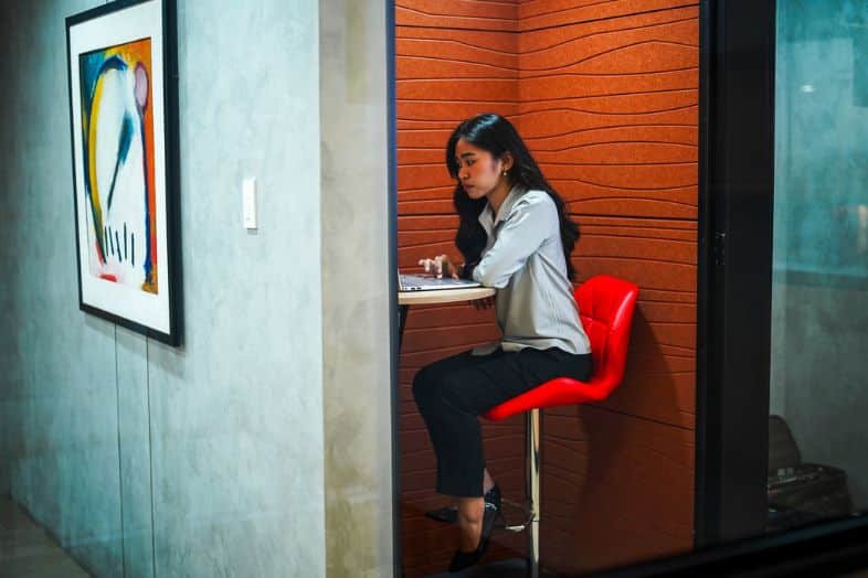 Woman working on laptop in a private coworking booth