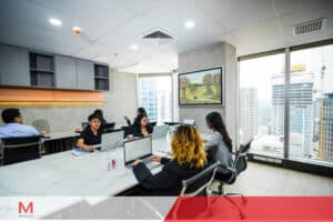 Several individuals of varying backgrounds gathered at a table in an office.