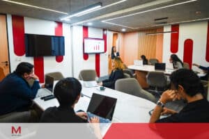 Team meeting and presentation inside an M Spaces coworking space, with professionals working on laptops around shared tables.